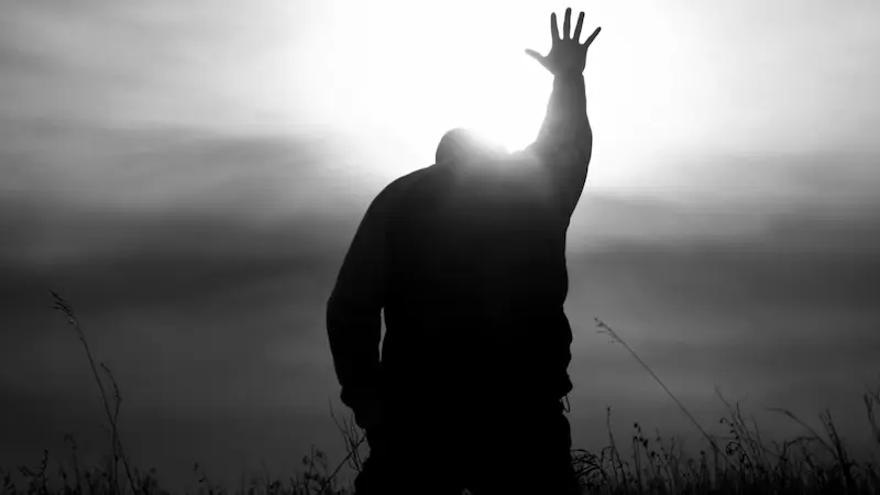 後向きの男性が右手を光に向かってあげている