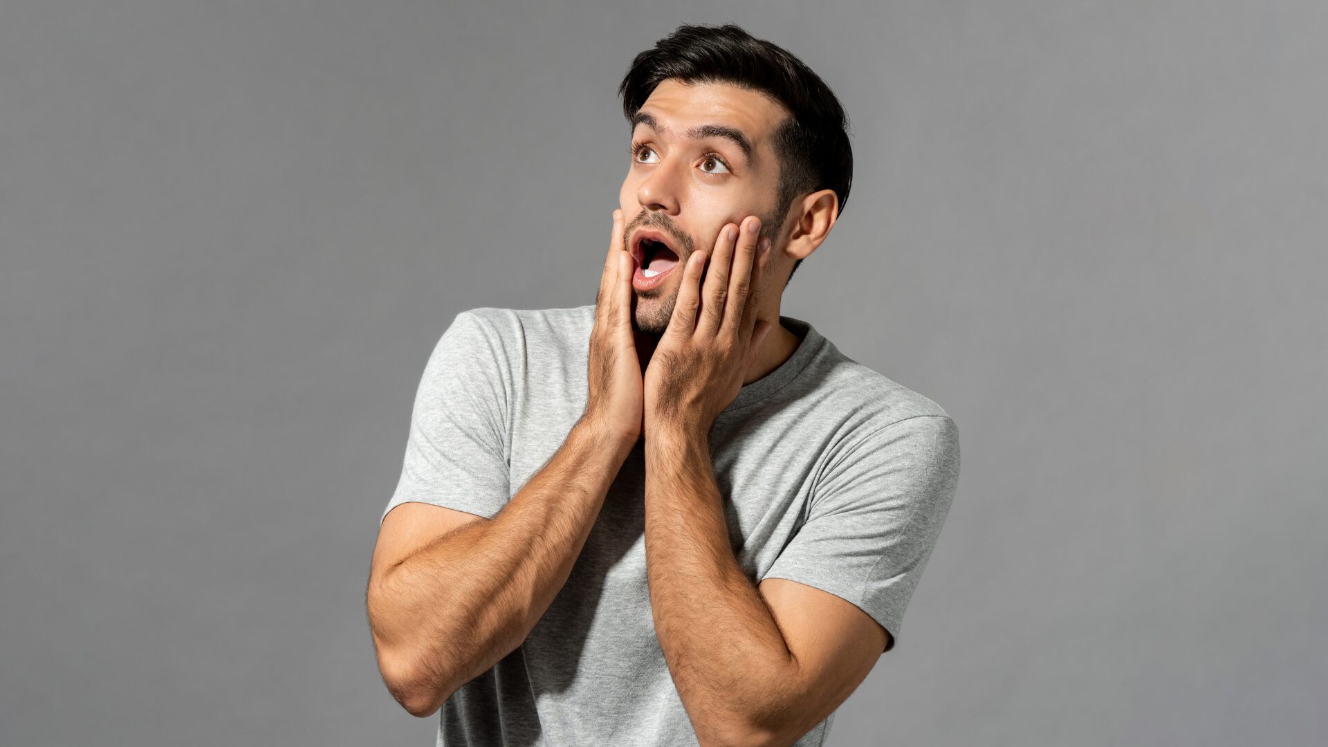 男性が驚いて両手をほほに当てている