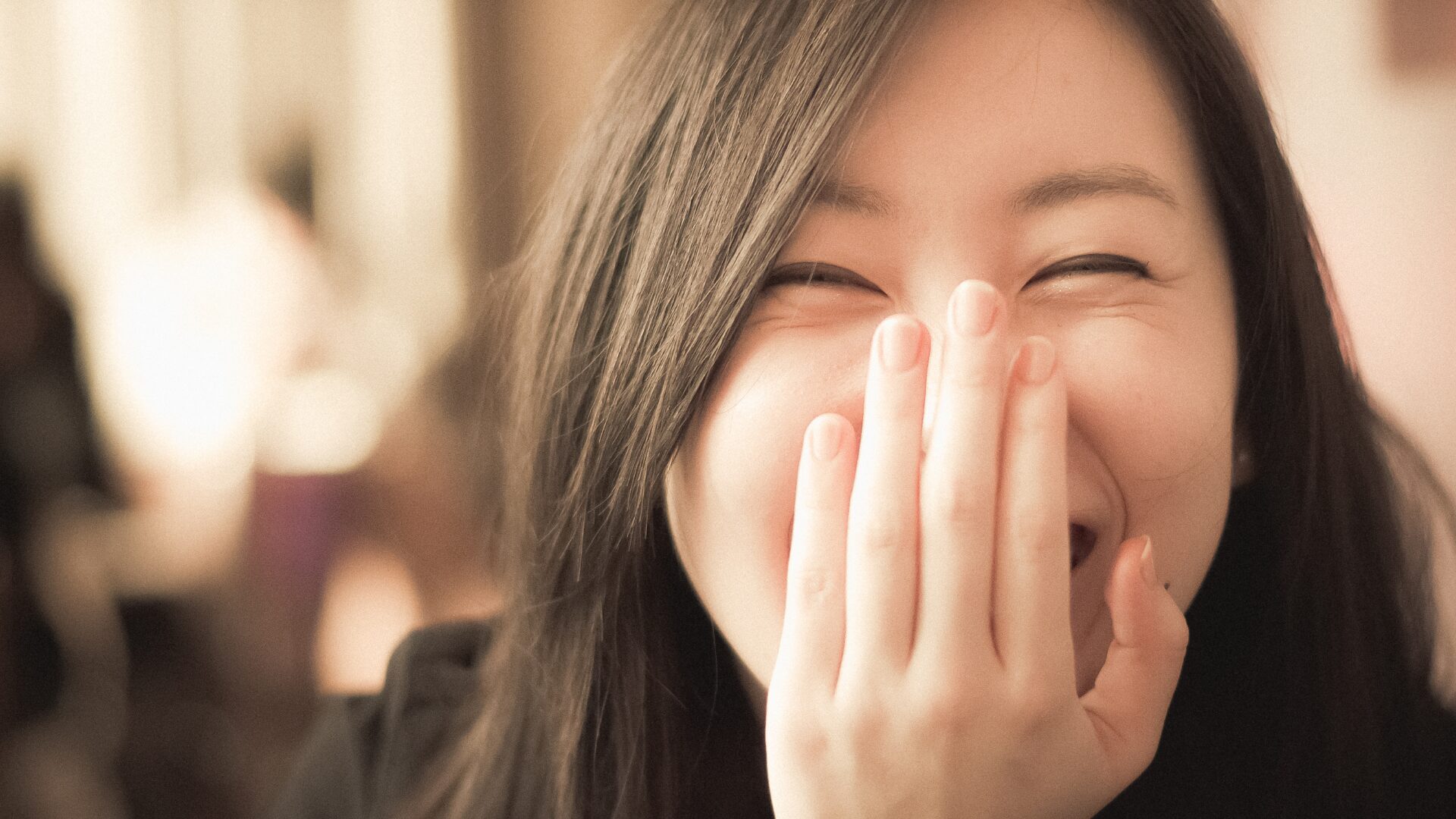 女性が口に手をあてて笑っている