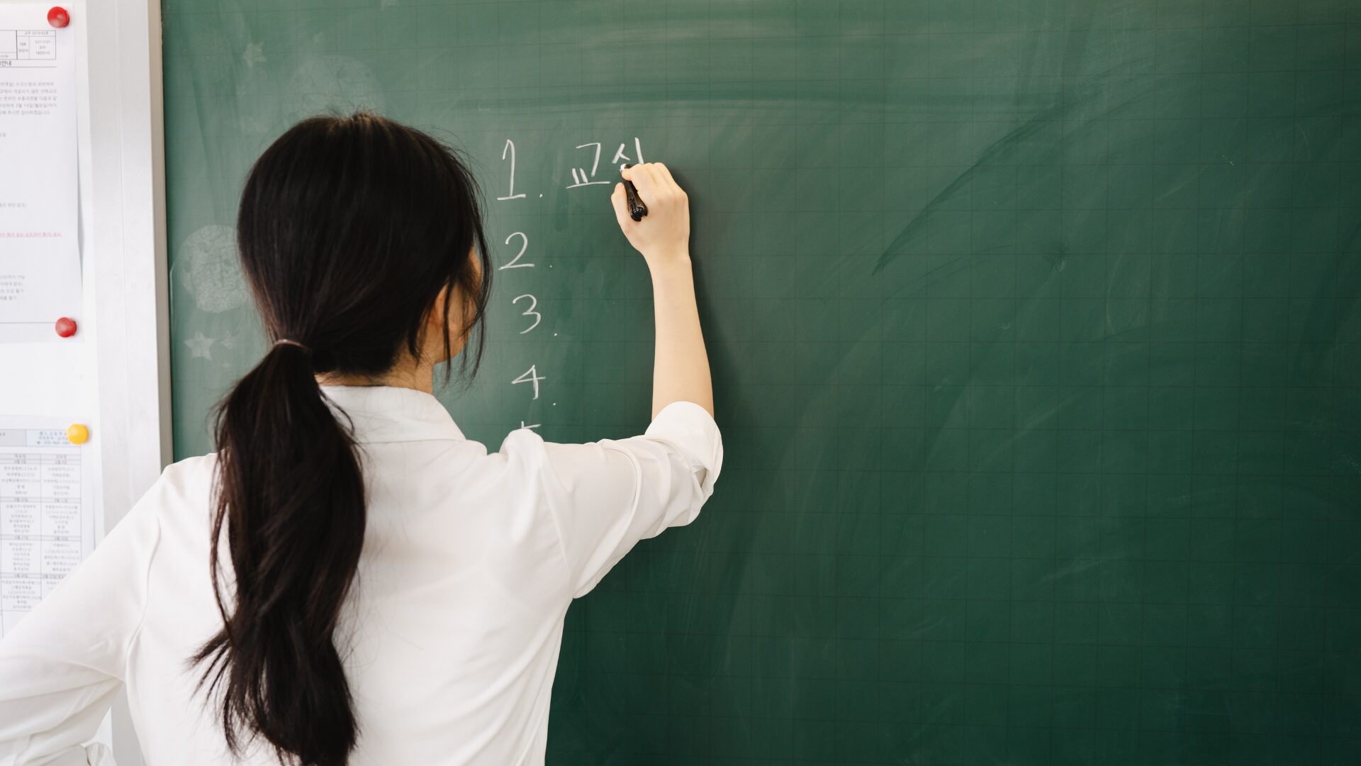 女性教師が黒板に文字を書いている