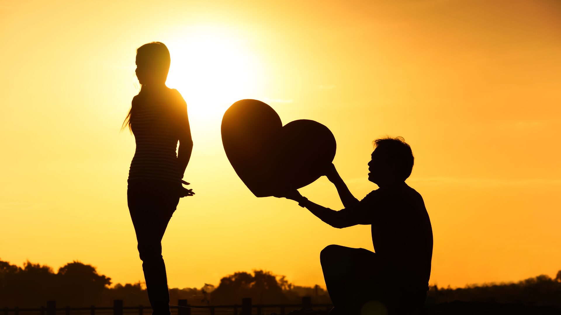 男性がひざまずきハートのオブジェを持って女性に捧げている