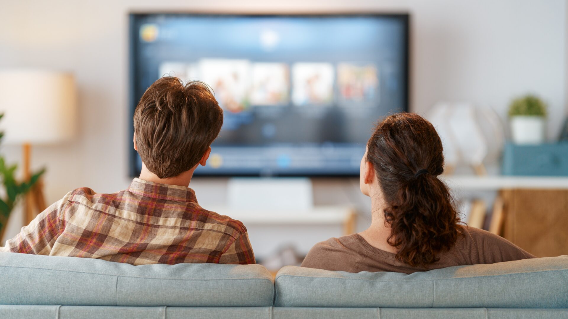 男女がソファーに寄り添ってテレビを見ている