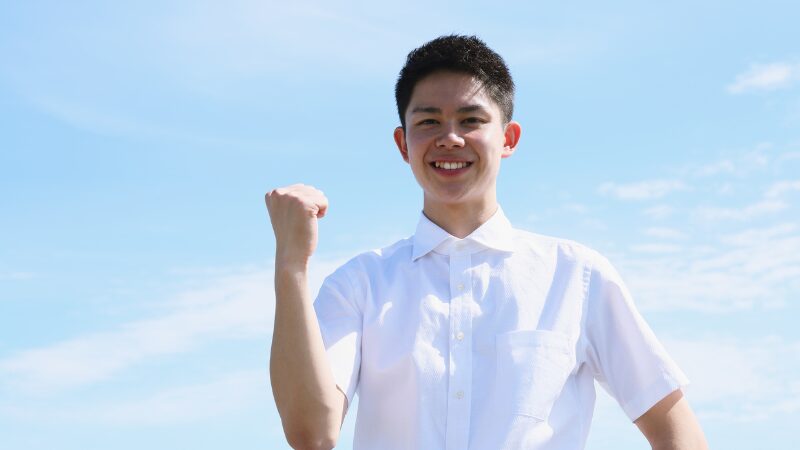 若い男性が右手でガッツポーズをしている